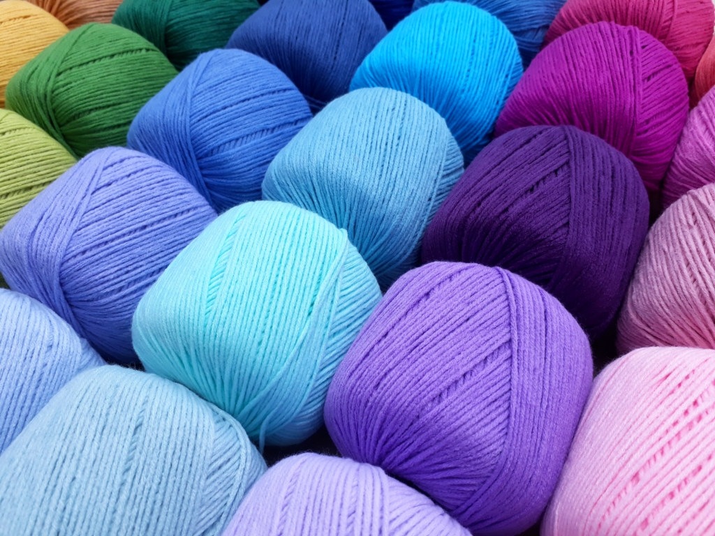 Colorful yarns of wool laid out in rows at a market storefront.