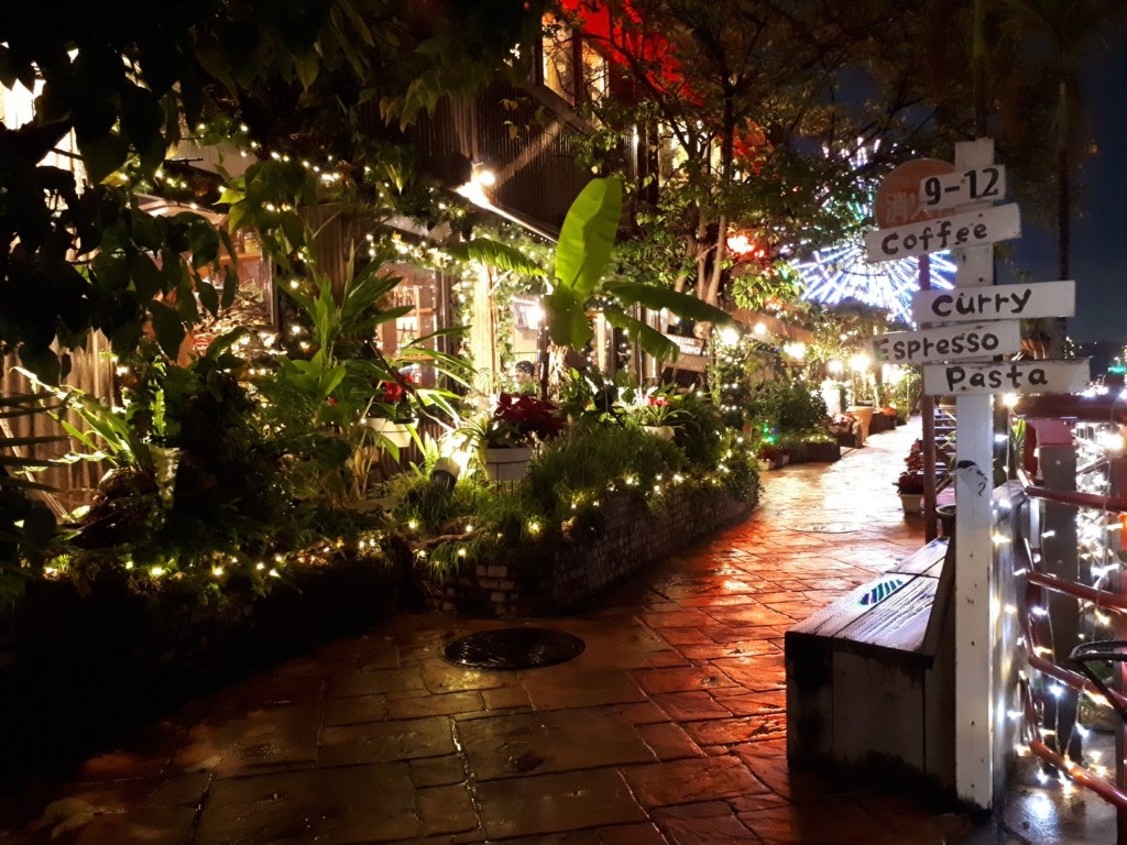 The outside of a small restaurant in the city illuminated with lights