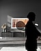 The Frame is installed on the wall of a dimly lit room. The dark shadow of a woman is in the foreground.