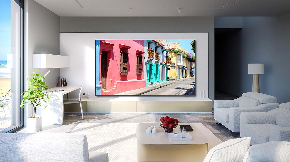 A 98 inch Supersize TV is mounted on a wall in a living room displaying colorful buildings.