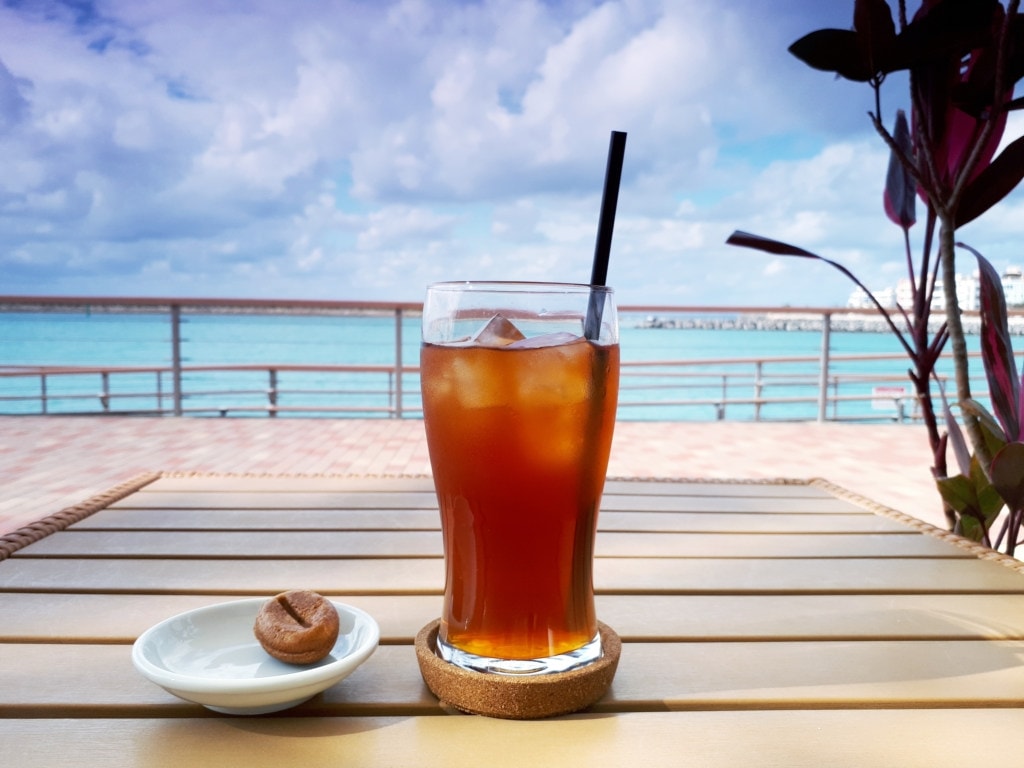 یک نوشیدنی تابستانی خنک قرار گرفته روی میز یک تراس مشرف به ساحل گرمسیری