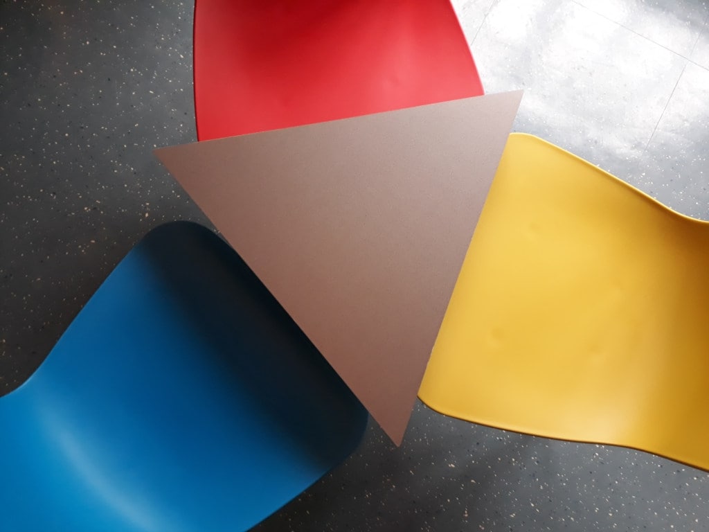 Overhead view of three colorful chairs around a triangular table in an avant garde cafe.