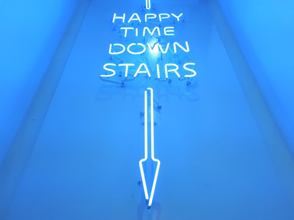 A blue neon sign lights up the entrance of a downtown bar.