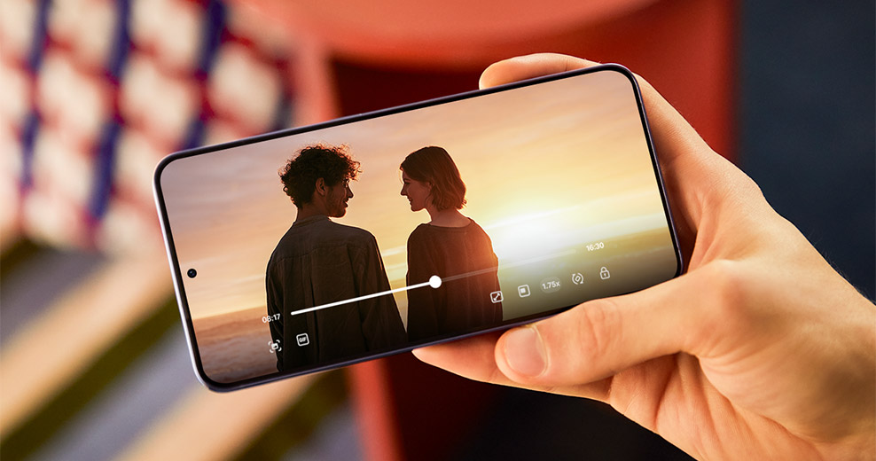 Galaxy S24 plus is held outdoors in the sunlight. A video with rich colour and high contrast plays on the screen.
