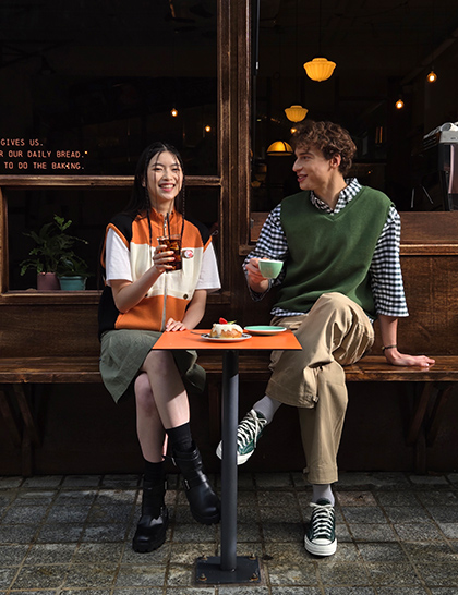 A colour rich photo of two people sitting in front of a cafe taken at 2x zoom.