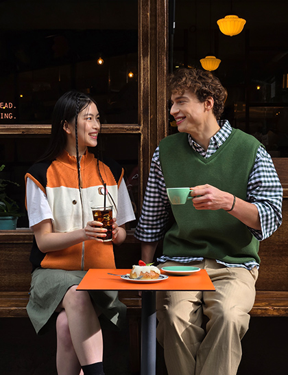 A colour rich photo of two people sitting in front of a cafe taken at 3x zoom.