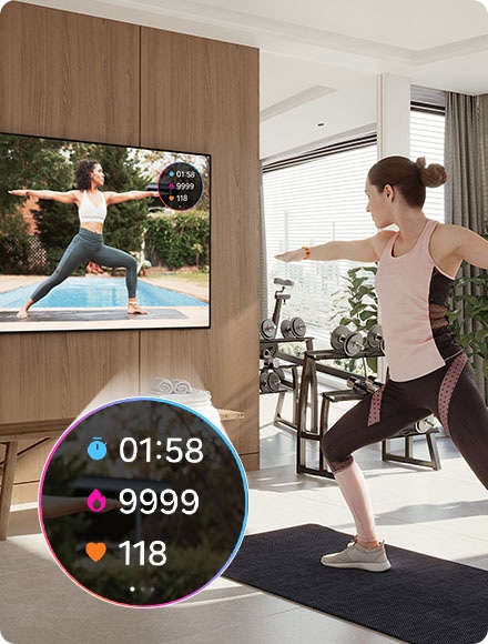 Une femme fait du yoga tout en regardant un entraîneur à la télévision. La télévision affiche également les statistiques de l'exercice 01:58, 9999, 118 de la Galaxy Watch connectée.