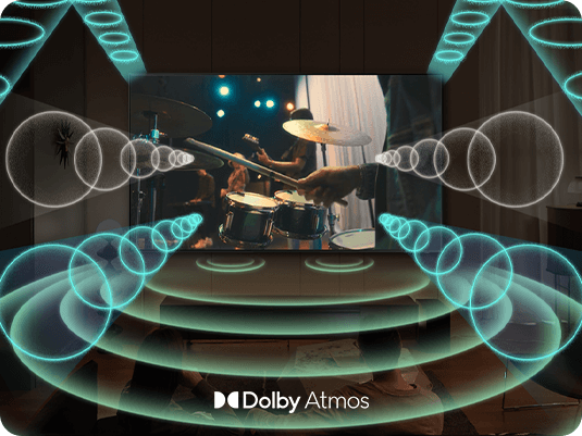 دوو کەس سەیری تەلەفزیۆنێکی Samsung OLED 2024 خاوەن تایبەتمەندی Dolby Atmos دەکەن، لە کاتێکدا دەنگی تەلەفزیۆن بۆشایی دەوروبەریان پڕدەکاتەوە.