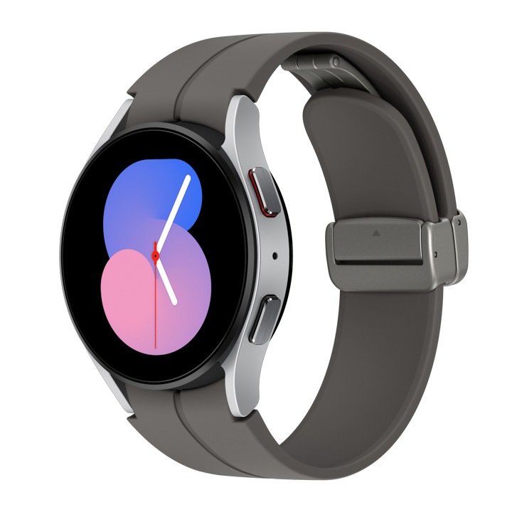 A silver Galaxy Watch5 with a grey D-Buckle sport band is shown at a tilted angle.