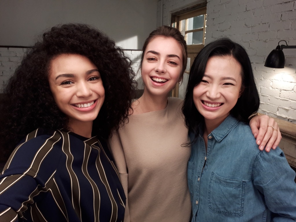 Selfie group shot of smiling models on set.